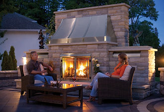 Ouside fireplace in a backyard with a middle-aged couple.