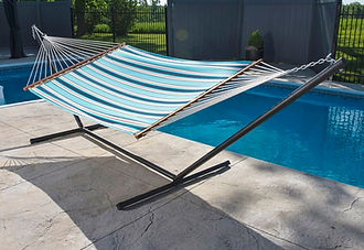 Hammok with blue stripes next to a pool in the summertime.