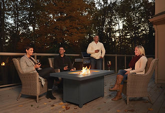 Patio table with a fire pit with two couples enjoying the outside weather in the evening.